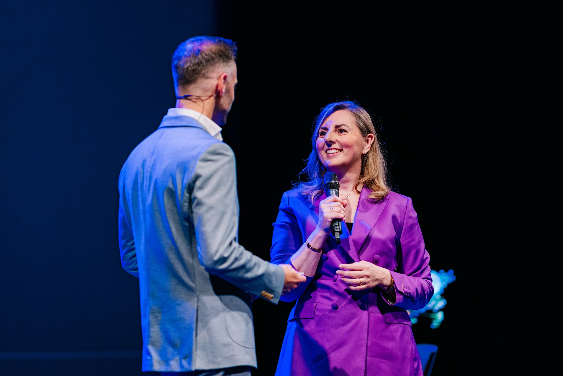 Melike Durmaz als dagvoorzitter in gesprek met een spreker op het podium.